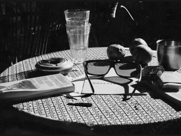 A dark, bleak cafe table with various items strewn across it