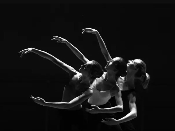 Three women dancing in a row with arms loosely encircling each other